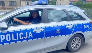 widzimy policjanta siedzącego w radiowozie.