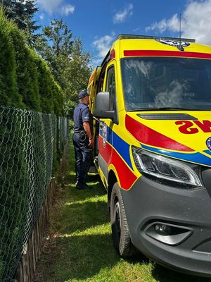 widzimy policjanta stojącego przy karetce pogotowia.