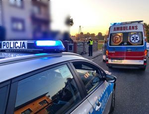 Policjant stoi przy hulajnodze, obok radiowóz, a w tle dom.