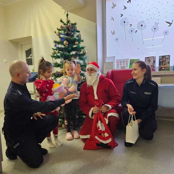 widzimy policjantów wraz z dziećmi i Świętym Mikołajem w sali.