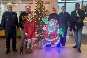 widzimy policjantów dziewczynkę oraz osoby dorosłe zaangażowane w akcję stojących przy choince.