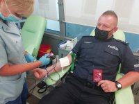 policjant oddający krew, siedzi na stanowisku w Krwiobusie