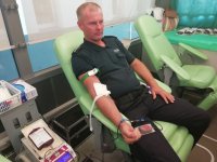 policjant oddający krew, siedzi na stanowisku w Krwiobusie