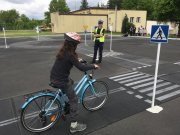 plac miasteczko ruchu drogowego, policjantka prowadzi egzamin dla uczniów na kartę rowerowa. uczeń pokonuje plac manewrowy