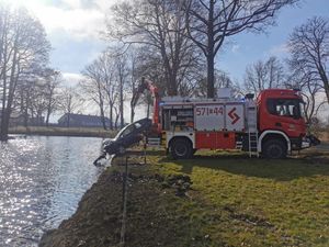 auto które wpadło do fosy, z wody wyciągane jest przez strażaków