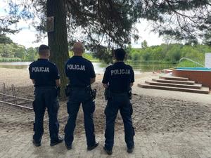 trzech policjantów stojących w pobliżu plaży i zbiornika wodnego