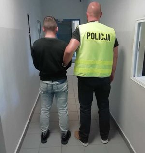 policjant prowadzi zatrzymanego mężczyznę. zdjęcie zrobione na korytarzu komendy