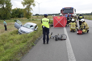 droga po wypadku, w rowie auto, na drodze rower i parawan oraz policjantka i strażacy