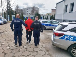 policjanci prowadzą zatrzymanego mężczyznę