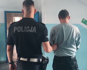 policjant, który prowadzi zatrzymanego mężczyznę. zdjęcie zrobione w pomieszczeniu służbowym