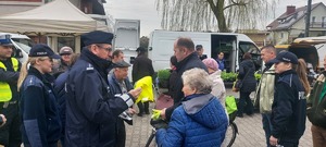 akcja rozdawania kamizelek odblaskowych na targowisku w Szczercowie. Policjanci i wojt gminy ubierają pieszych i rowerzystów w kamizelki