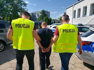 policjanci prowadzą zatrzymanego mężczyznę.