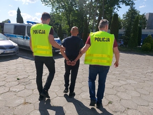 policjanci prowadzą zatrzymanego mężczyznę.