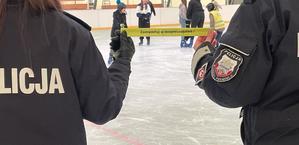 dwie policjantki na lodowisku, trzymają opaskę odblaskową z napisem zainwestuj w bezpieczeństwo.