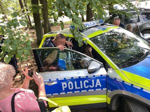 spotkanie policjanta z dziećmi, młodzieżą i mieszkańcami na pikniku organizowanym przez funkcjonariuszy straży leśnej.