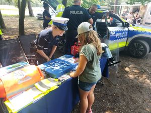 spotkanie policjanta z dziećmi, młodzieżą i mieszkańcami na pikniku organizowanym przez funkcjonariuszy straży leśnej.