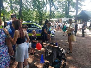 spotkanie policjanta z dziećmi, młodzieżą i mieszkańcami na pikniku organizowanym przez funkcjonariuszy straży leśnej.