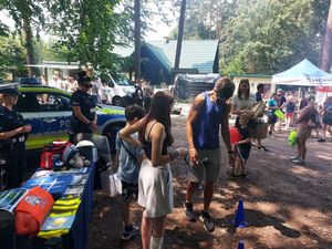 spotkanie policjanta z dziećmi, młodzieżą i mieszkańcami na pikniku organizowanym przez funkcjonariuszy straży leśnej.