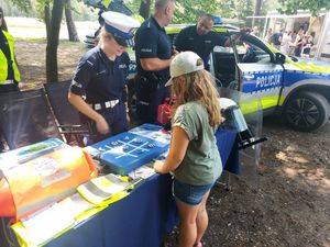 spotkanie policjanta z dziećmi, młodzieżą i mieszkańcami na pikniku organizowanym przez funkcjonariuszy straży leśnej.