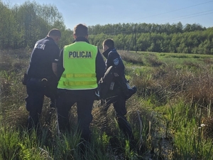 Na zdjęciu policjanci pomagają zaginionemu wydostać się z mokradeł.