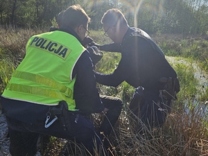 Na zdjęciu policjanci pomagają zaginionemu wydostać się z mokradeł.