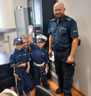 policjant i dwoje przedszkolaków przebranych za policjanta. wszyscy w pomieszczeniu służbowym posterunku policji.