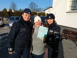 Policjantki z seniorką, która trzyma w ręku ulotkę.
