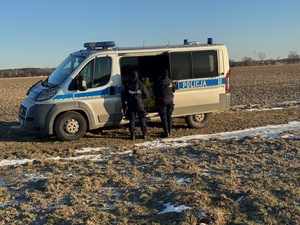 Policjantki stoją tyłem przy radiowozie.