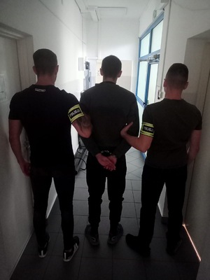Policjanci trzymają zatrzymanego.