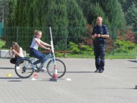 egzamin na kartę rowerową, uczeń na rowerze pokonuje tor przeszkód pod okiem policjanta