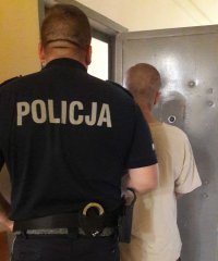 zatrzymany za posiadanie narkotyków, policjant wprowadza podejrzanego do pomieszczenia dla zatrzymanych