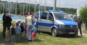 radiowóz policyjny, obok dzieci i policjanci. spotkanie w ramach bezpiecznych wakacji
