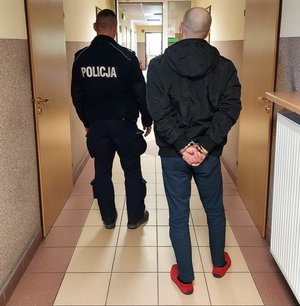 umundurowany policjant prowadzi zatrzymanego mężczyznę