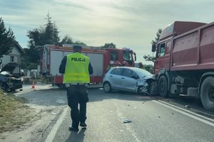 umundurowany policjant ruchu drogowego stoi na drodze, a w tle rozbite auta