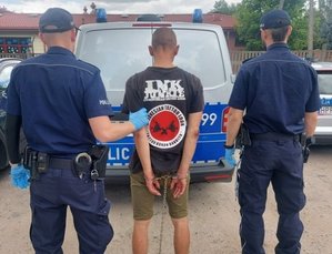 umundurowani policjanci prowadzą zatrzymanego mężczyznę