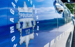srebrne logo policji na niebieskich drzwiach oznakowanego radiowozu.