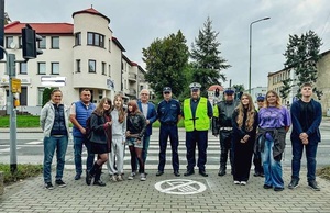 wszyscy uczestnicy przedsięwzięcia stoją w tle przed piktogramem.