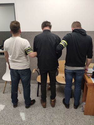 Zatrzymany mężczyzna trzymany przez funkcjonariuszy.