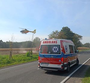 Ambulans, w tle odlatujący śmigłowiec.