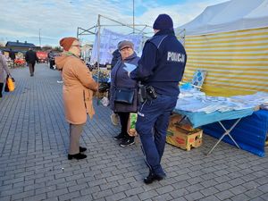 Dzielnicowy rozdający odblaski na targowisku.