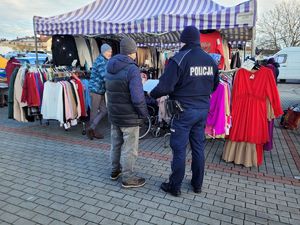 Dzielnicowy rozdający odblaski na targowisku.