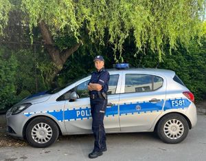 Policjantka stojąca przed radiowozem.