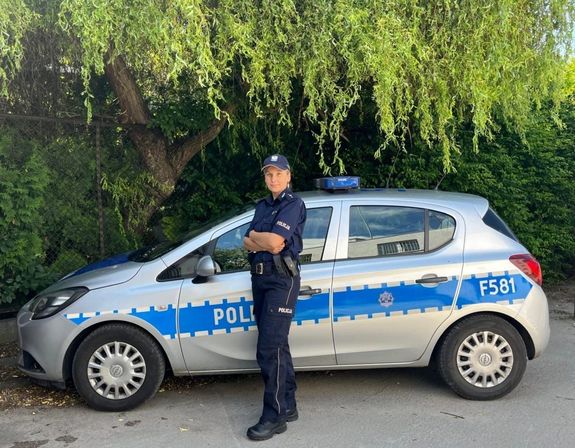 Policjantka stojąca przed radiowozem.