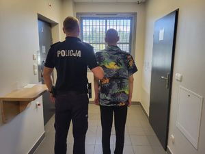 Zatrzymani obcokrajowcy trzymani przez policjanta.