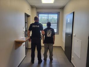 Zatrzymani obcokrajowcy trzymani przez policjanta.