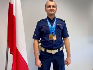 Policjant na podium, zdjęcie przedstawiające umundurowanego policjanta z dwoma medalami.