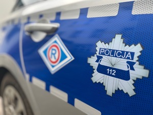 Logo Policji na drzwiach radiowozu.