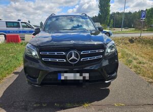 Czarny Mercedes, w tle radiowóz.