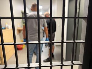 Za kratami stoi policjant i nieumundurowany policjant.
