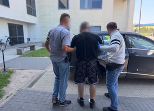 Dwóch nieumundurowanych policjantów z zatrzymanym mężczyzną.